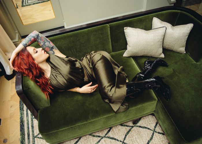 Mistress Adreena in a satin dress, laying on a velvet sofa