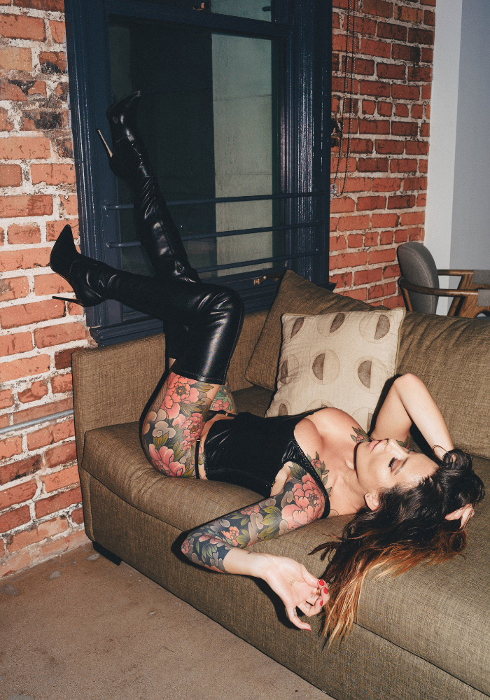 Adreena reclined on a sofa with her black leather high-heals.